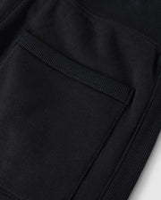 Close-up of a textured black fabric pocket with visible stitching on cozy fleece, highlighting detailed craftsmanship on Psycho Bunny's KIDS LEVY ESSENTIAL FLEECE SWEATPANT - B0P721D200.