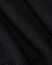 A close-up of the Psycho Bunny KIDS LEVY ESSENTIAL FLEECE SWEATPANT (B0P721D200) in black showcases a textured knit pattern with soft folds and dense weave, suggesting the warmth and comfort ideal for cozy fleece fabric.