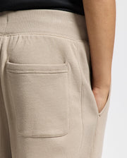 A person stands against a neutral background wearing the Psycho Bunny KIDS LEVY ESSENTIAL FLEECE SWEATPANT - B0P721D200. The lightweight fleece pants feature a textured elastic waistband, side pocket, and back pocket, providing a cozy feel.