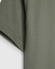 The KIDS CLASSIC CREW NECK TEE - B0U014B200 by Psycho Bunny, in olive green, showcases sleeve and side details on a plain white background. Made from 100% Pima cotton, its texture and stitching make it an ideal back-to-school choice.