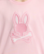 The KIDS NEW CASTLE EMBROIDERED GRAPHIC TEE by Psycho Bunny is a pink shirt made from premium Pima cotton, featuring an embroidered Bunny logo with a stylized head and long ears over two crossed bones, resembling a fun skull-and-crossbones graphic.
