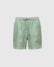 The Psycho Bunny KIDS BENDIGO ALL OVER PRINTED SWIM TRUNK (B0W619F200) features light green quick-dry fabric with white circular dots, an elastic waistband, and a drawstring tie. Displayed on a plain white background.