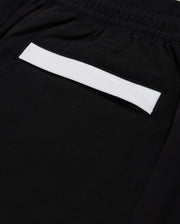 Close-up of a black fabric pocket on Psycho Bunny's KIDS PARKER HYDROCHROMIC SWIM TRUNK - B0W646C200, featuring an elastic waistband. The pocket highlights a white rectangular strip across its top edge and is made from quick-dry material.