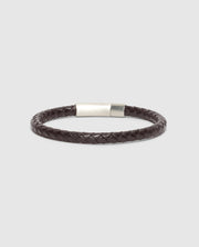 The MEN'S BRAIDED LEATHER BRACELET - B6A371E200 by Psycho Bunny features an elegant dark brown design with a silver clasp, beautifully showcased on a light gray background.