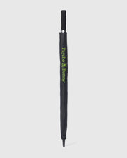 A black GOLF UMBRELLA - B6A624C200 with a protective cover. The cover features the text "Psycho Bunny" and a small bunny logo in green, vertically aligned along the length of this reliable umbrella. The handle is black with a grip texture. The umbrella is standing upright against a white background.