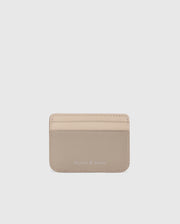 The MENS LEATHER CARD CASE - B6A869D200 by Psycho Bunny is a premium beige leather cardholder with three front slots and a silver "Psycho Bunny" embossing near the bottom center, minimal edge stitching on a plain light gray background.