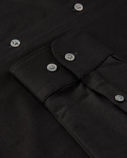 Close-up of the MENS ARTHUR JERSEY SHIRT - B6C748D200 by Psycho Bunny, made from stretch Pima cotton with a detailed view of buttons and stitching. The image prominently features four silver buttons and a pocket flap with a similar button, showcasing the texture and craftsmanship of the jersey fabric.