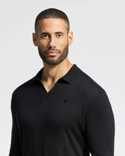 A man with short hair and a beard is wearing a Psycho Bunny black MENS JOHNNY COLLAR SWEATER - B6E258E200 made from a cotton-wool blend, featuring a small logo on the left, as he looks into the camera against a plain light background.