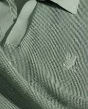 The Psycho Bunny MENS LEETON JOHNNY COLLAR KNIT POLO (B6E562F200) is a sage green cotton polo featuring a Johnny collar and an embroidered Bunny with crossbones logo on the chest.