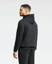 A man stands to the side wearing a Psycho Bunny Men's New Castle Embroidered French Terry Hoodie (B6H517F200) with matching pants. His hoodie’s relaxed fit highlights his short hairstyle against a light background, embodying a modern New Castle vibe.