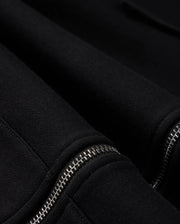 Here's a close-up shot of the MENS LEVY ZIP FLEECE HOODIE by Psycho Bunny, showcasing its black cotton fabric and two distinctive silver zippers. The contrast between the soft texture of the hoodie and the metallic sheen of the zippers highlights these intricate details on this men's zip hoodie.