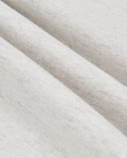 Close-up of a gently folded, light gray fabric from the MENS JAMES PREMIUM HOODIE - B6H789D200 by Psycho Bunny, showcasing its soft texture and subtle specks. The folds create slight shadows that accentuate the material's smoothness and fine weave.