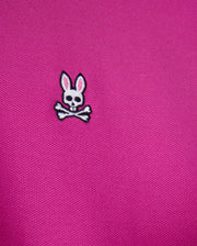 The Psycho Bunny MENS CLASSIC PIQUE POLO SHIRT - B6K001D200 features pink textured 100% Pima cotton with an embroidered white skull and crossbones topped with rabbit ears.