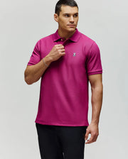 A man in a Psycho Bunny MENS CLASSIC PIQUE POLO - B6K001F200, featuring soft Pima cotton and an embroidered Bunny logo, paired with black pants, stands against a light gray background looking to his left.