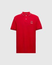 The Psycho Bunny MENS PIERCE PIQUE POLO - B6K201E200 is a red polo shirt made from Pima cotton and features an embroidered bunny logo on the left chest, along with striped details on the collar and sleeves.