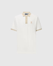 The Psycho Bunny MENS NEW CASTLE PIQUE POLO (B6K487F200) is a slim-fit, short-sleeve off-white polo with beige contrast on the collar, cuffs, and placket, plus an embroidered bunny logo on the chest. Displayed on a light gray background.