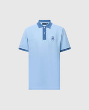 The MENS NEW CASTLE PIQUE POLO - B6K487F200 by Psycho Bunny is a light blue slim-fit polo made of premium Pima Cotton. It features a textured darker blue collar and cuffs, a two-button placket, and an embroidered rabbit emblem on the left chest against a plain white background.
