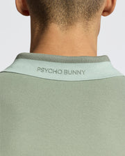 Back view of a person wearing the MENS NEW CASTLE PIQUE POLO - B6K487F200 in light green, featuring "PSYCHO BUNNY" on the collar, crafted from soft Pima Cotton with luxury finishes.