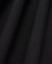 Close-up of the black Pima cotton fabric under soft lighting, showcasing the fine weave and subtle folds of Psycho Bunny's MENS JAMES PREMIUM PIQUE POLO SHIRT - B6K945D200. The surface appears smooth and uniform, with shadows emphasizing the gentle undulations typical of this high-quality polo shirt.
