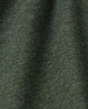 Close-up view of the textured fabric in a dark green color. The high-quality MENS JAMES PREMIUM PIQUE POLO SHIRT by Psycho Bunny features a soft, slightly fuzzy surface with fine threads woven tightly together, creating a subtle diagonal pattern. The lightweight pima cotton material appears slightly draped, showing gentle folds.