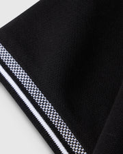 Close-up of a black fabric with an intricate, diamond-knit texture from the Psycho Bunny MENS MALTON PIQUE POLO SHIRT - B6K950D200. The edge showcases a striking white and black patterned border that forms a contrasting stripe. The fabric exudes softness and has a slightly raised surface, embodying the premium quality typical of Psycho Bunny designs. The background is light-colored.