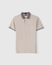 The Psycho Bunny Men's Malton Pique Polo Shirt (B6K950D200) is made from light beige Pima cotton and features a stylish gray collar and sleeve cuffs. It includes a sleek, buttoned placket, sporty trim details, and an embroidered Psycho Bunny logo on the left chest.