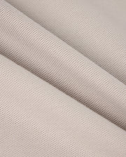 Close-up of a folded piece of beige fabric from the MENS MALTON PIQUE POLO SHIRT - B6K950D200 by Psycho Bunny. The textured material features a fine, even mesh pattern, reminiscent of a diamond pique design. The folds in the fabric create diagonal lines that add depth and dimension to the image. The material appears soft and slightly porous, making it potentially suitable for clothing or upholstery applications.
