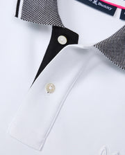 A close-up of the MENS MALTON PIQUE POLO SHIRT - B6K950D200 from Psycho Bunny showcases a textured, black-and-white checkered collar complemented by a contrasting black placket with two white buttons. The shirt's fabric features a subtly embroidered logo, enhancing this piece's refined elegance.