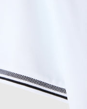 A close-up image of the MENS MALTON PIQUE POLO SHIRT by Psycho Bunny reveals a white fabric with a textured diamond pique pattern, accented by a black and white patterned trim along the edge. The design reflects Psycho Bunny's signature attention to detail, ensuring a smooth and polished finish similar to their timeless Pima cotton polo creations.