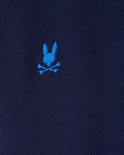 The MENS KENT PIQUE POLO SHIRT (B6K951D200) by Psycho Bunny is a stylish men's polo in navy, crafted from comfortable Pima cotton pique. It boasts a unique touch with a small, bright blue embroidered rabbit head over crossed bones.
