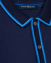A close-up of the stylish MENS KENT PIQUE POLO SHIRT by Psycho Bunny showcases its navy blue color with light blue trim on the collar and placket. This comfortable polo features a small "Psycho Bunny" label under the collar and a two-button placket.
