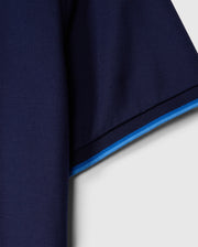 Close-up of the Psycho Bunny MENS KENT PIQUE POLO SHIRT - B6K951D200, showcasing the dark blue fabric sleeve with a light blue trim. The Pima cotton texture is visible against a light background.