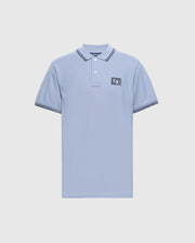 The Psycho Bunny MENS MONROE PIQUE POLO (B6K964D200) in regular fit showcases a light blue hue with a collar, two buttons, and logo appliqué crest on the left chest. Dark blue stripes accent the collar and sleeve edges against a plain white background.