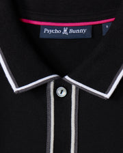 A detailed view of the Psycho Bunny Men's Kent Long Sleeve Pique Polo in black showcases its sophisticated design, featuring a button and white and gray striped accents on the collar and placket. Made from high-quality Pima cotton, it includes a "Psycho Bunny" label inside the collar.