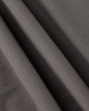 Close-up of smooth, dark grey fabric with soft wrinkles and folds, showcasing the fine texture and matte finish. This material, part of the MENS MADISON COMMUTER PANT - B6P395Z1WB by Psycho Bunny, creates a sense of depth and shadow throughout the image. Look closely to find subtle bunny detailing that adds a unique touch.