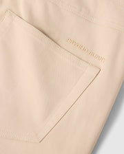 Close-up of the MENS MAVERICK 10K PANT - B6P788D200 pocket, showcasing the small embroidered "PSYCHO BUNNY" text in gold thread near the top edge. The fabric appears smooth, with clean stitching outlining the five-pocket pant's shape and offering four-way stretch for ultimate comfort.
