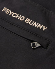 Close-up of a black fabric with "Psycho Bunny" embroidered in white thread. Below the text is a zipper with a small bunny icon on the metal pull tab. Made from a soft cotton-blend for ultimate comfort, the fabric is part of the MENS JAMES PREMIUM SWEATPANT - B6P791D200 by Psycho Bunny.