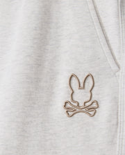 Zoom in on the soft, heathered cotton-blend fabric of the MENS JAMES PREMIUM SWEATPANT - B6P791D200 from Psycho Bunny, featuring a stitched emblem. The bunny head with elongated ears above crossed bones resembles a pirate symbol in light brown thread, offering perfect comfort for any sweatpant design.