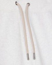 Close-up of the Psycho Bunny MENS JAMES PREMIUM SWEATPANT - B6P791D200 in a light gray cotton-blend, featuring beige drawstrings with metal tips nestled against the plush fabric. The texture is prominently visible, while the drawstring holes are reinforced with metal eyelets, perfectly embodying both style and comfort.