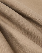 Close-up of the light brown twill fabric from the MENS HAYS TWILL PANT (B6P894D200) by Psycho Bunny, featuring a diagonal weave pattern. The material is slightly draped to highlight its texture and soft folds, offering ultimate comfort.