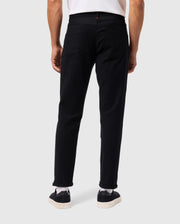 Rear view of a person showcasing ultimate comfort in Psycho Bunny's MENS HAYS TWILL PANT - B6P894D200, paired with sleek black sneakers featuring white soles, and a white shirt. The ensemble stands out against a light grey background.