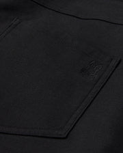 Close-up of the Psycho Bunny MENS HAYS TWILL PANT in black, made from a cotton-blend twill. It features a pocket adorned with an embroidered rabbit logo in the corner. The fabric has a textured appearance and provides ultimate comfort with its 4-way stretch design.