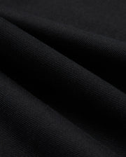Close-up of the black cotton-blend twill fabric used in the MENS HAYS TWILL PANT - B6P894D200 by Psycho Bunny, featuring diagonal lines that highlight its textured surface and smooth folds. The material appears thick and finely woven, providing ultimate comfort while subtly reflecting light.
