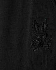 A close-up of the black fabric on our Psycho Bunny MENS PACIFIC CHENILLE JOGGER - B6P972D200 showcases an embroidered design featuring a skull and crossbones with a rabbit face and long ears, perfectly complementing the laid-back vibe of our casual jogger line.