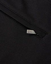 Close-up of a black fabric showcasing a small silver zipper pull with an engraved rabbit design. The zipper is partially open, providing a glimpse of the Psycho Bunny MENS PACIFIC CHENILLE JOGGER - B6P972D200 underneath, highlighting its casual bottom and unique chenille logo patch.