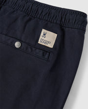 Close-up of navy blue pants featuring an elastic waistband, a back pocket with a button closure, and a beige patch with a bunny logo and the text "PSYCHO BUNNY." These comfortable MENS WILLIS STRETCH TENCEL SHORT - B6R239Y1WB by Psycho Bunny combine style and functionality effortlessly.