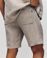 Wearing Psycho Bunny's MENS WINDCREST LINEN BLEND DRAWSTRING SHORT - B6R474C200, a person poses with one hand on their hip, highlighting the textured fabric and back pocket for an effortless summer style.