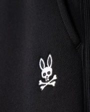 Close-up of the Psycho Bunny MENS LEVY FLEECE SWEATSHORT - B6R862D200, a black cotton fleece sweatshort with an embroidered white logo featuring a rabbit head with crossbones underneath.