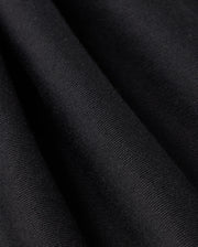 Close-up of the black French terry fabric from the MENS LEVY FLEECE SWEATSHORT - B6R862D200 by Psycho Bunny, showcasing its visible texture. The smooth, velvety surface of the fabric is draped in gentle folds, with lighting that highlights the subtle differences in texture and shading.