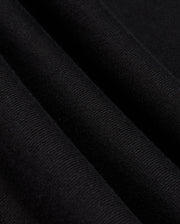 Close-up of the folded black cotton jersey fabric from the Psycho Bunny MENS KINGSTON SWEATSHIRT - B6S480D200, showcasing its fine, textured weave. The folds produce subtle shadows and highlights that enhance the texture and drape of the material, reminiscent of tonal embossing.